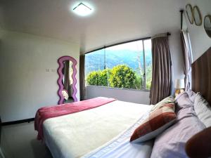 ein Schlafzimmer mit einem Bett mit einem großen Fenster in der Unterkunft CASA VISTA HERMOSA in Baños