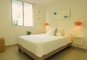 une chambre avec un grand lit blanc avec une fenêtre dans l'établissement Beautiful oasis of peace in the heart of Pradomar!, à Puerto Colombia 22 autres photos