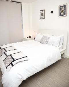 1 dormitorio blanco con 1 cama blanca grande con almohadas en OBI'S House&Suites - Luxury 2bed Duplex Apartment With Balcony, en Mánchester