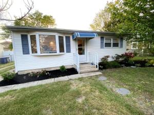 ein kleines weißes Haus mit einer Veranda und einem Hof in der Unterkunft Cape Bay Cottage in Cape May