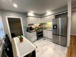 eine Küche mit einem Edelstahlkühlschrank und weißen Schränken in der Unterkunft Cape Bay Cottage in Cape May