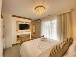 a bedroom with a white bed and a television at Pousada Villa Vie in Gramado