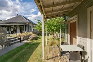eine Terrasse mit einem Tisch und Stühlen auf einem Haus in der Unterkunft Kiwi Ski Cottage - Wanaka Holiday Home in Cardrona