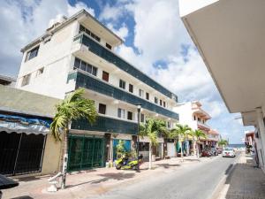 a tall white building on a street with palm trees at Hotel cacao spa cozumel in Cozumel