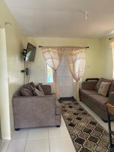 a living room with two couches and a window at Sasha’s Holiday Home Oistins Barbados in Christ Church