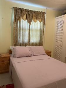 a bedroom with a large bed with a window at Sasha’s Holiday Home Oistins Barbados in Christ Church