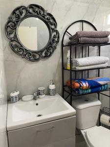 a bathroom with a sink and a mirror and a toilet at Sasha’s Holiday Home Oistins Barbados in Christ Church