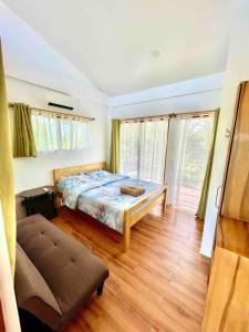 a bedroom with a bed and a couch and windows at Exclusive House Pool in Panglaoo in Panglao +8 photos