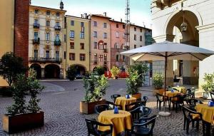 an outdoor patio with tables and chairs and an umbrella at B&B del centro in Pinerolo
