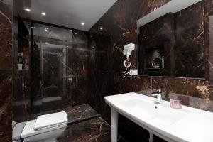 a bathroom with a sink and a mirror and a toilet at Aparthotel Hilton Blox in Tbilisi City +88 photos
