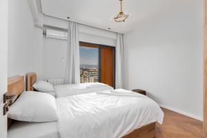 a white bedroom with two beds and a window at Aparthotel Hilton Blox in Tbilisi City