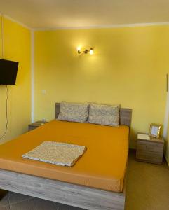 a bedroom with an orange bed with a yellow wall at Fenix Apartmani Dubrava in Dobra Voda