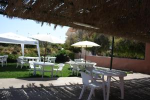 grupa stołów i krzeseł z parasolami w obiekcie Hotel Castelsardo Domus Beach w mieście Castelsardo