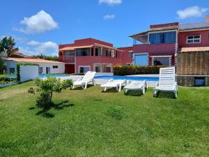 a group of chairs sitting in the grass in front of a house at Apartamento Céu Azul in Porto Seguro