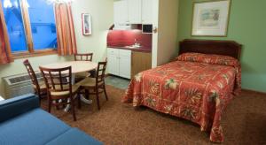 a room with a bed, table, chairs and a television at Calypso Boutique Hotel in Wildwood