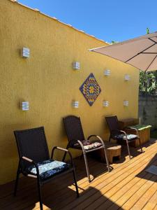 three chairs and an umbrella on a wooden deck at Suítes Vila Jjae in Praia do Rosa