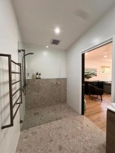 ein Badezimmer mit ebenerdiger Dusche neben einem Wohnzimmer in der Unterkunft Cottage Hill Creek near the beach and bush in Macmasters Beach