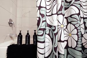 a bathroom with a shower curtain with bottles on a shelf at Downtown Suite King Beds,Long Stays,Disney+ in Edmonton +48 photos