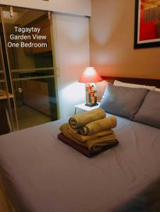 a pile of towels sitting on top of a bed at Tagaytay Cozy 1BR Wind Residences in Kaybagal