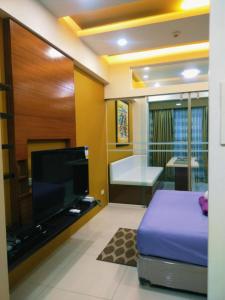 a bedroom with a tv and a bed and a bathroom at Tagaytay Cozy 1BR Wind Residences in Kaybagal