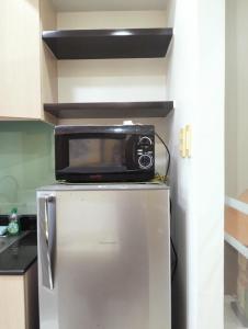 a microwave on top of a refrigerator in a kitchen at Tagaytay Cozy 1BR Wind Residences in Kaybagal