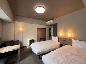 a hotel room with two beds and a couch at Hotel Route Inn Suzaka in Suzaka