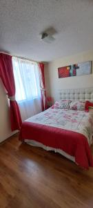ein Schlafzimmer mit einem Bett mit einer roten Decke und einem Fenster in der Unterkunft Departamento a pasos del Faro in La Serena