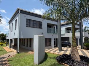 a white house with a palm tree in front of it at holiday villa in Harare