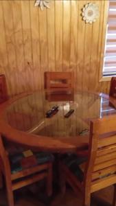 a glass table with two chairs and a wooden table at Patagon karim in Puerto Cahacabuco
