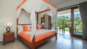a bedroom with a canopy bed and a balcony at Villa Yenian by Villa Finder in Canggu