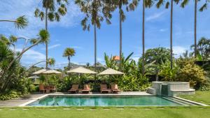 a pool at the resort with chairs and umbrellas at Villa Yenian by Villa Finder in Canggu