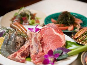 a plate of food with meat and vegetables on a table at 413 Hamahiga Hotel＆Cafe in Uruma