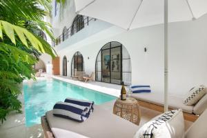 an indoor swimming pool with white walls and a white couch at Villa Sugi Umalas in Canggu