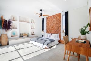 a bedroom with a bed and a table and a desk at Villa Sugi Umalas in Canggu