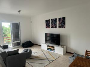 Una sala de estar con un sofá y un televisor. en Populo Beach Villa, en Livramento