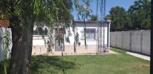 una casa con un árbol delante de una valla en Don cholo, en Buenos Aires