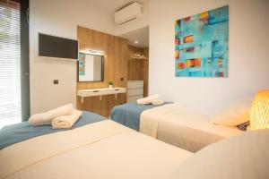 a bedroom with two beds and a painting on the wall at Allure Luxury Villas 2, Skiathos in Skiathos Town