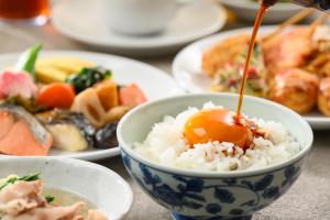 eine Schüssel Reis mit einem Ei darauf und Teller mit Essen in der Unterkunft Hotel Kansai in Osaka