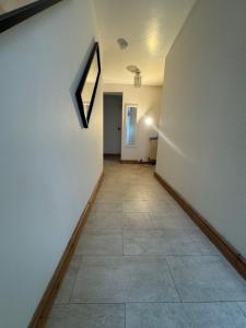 a hallway with a white wall and a tile floor at Peace House in Leeds