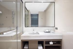 a bathroom with a sink and a mirror and a tub at Hyatt House Shanghai Hongqiao CBD in Shanghai
