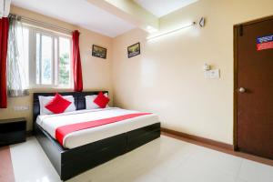 a bedroom with a bed with red pillows and a window at Collection O Tiara Near Christ university in Bengaluru