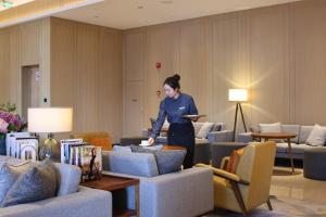 a woman standing in a room with couches at Hyatt House Shanghai Hongqiao CBD in Shanghai
