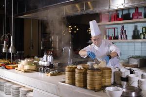 a chef preparing food in a restaurant kitchen at Hyatt House Shanghai Hongqiao CBD in Shanghai