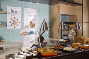 a chef standing in a kitchen preparing food at Hyatt House Shanghai Hongqiao CBD in Shanghai