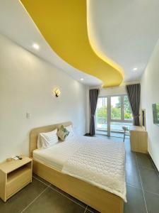 a bedroom with a bed and a yellow ceiling at Baly Hotel Bà Rịa City in Ba Ria