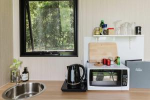 a kitchen counter with a microwave and a sink at Spring Haven Retreat by Tiny Away in Eureka