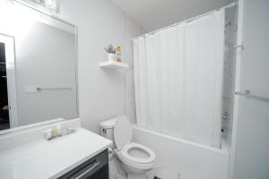 ein weißes Badezimmer mit Toilette und Dusche in der Unterkunft Entire 1 bed and Den Near YEG International Airport in Nisku