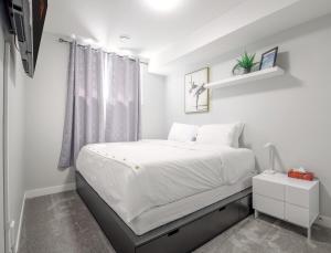 ein Schlafzimmer mit einem großen weißen Bett mit einem Fenster in der Unterkunft Entire 1 bed and Den Near YEG International Airport in Nisku