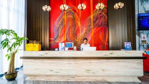 a person sitting at a desk with a laptop at Wansheng Hotel in Jingxi