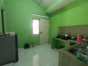 a green kitchen with a sink and a window at Kamila House in Bantul